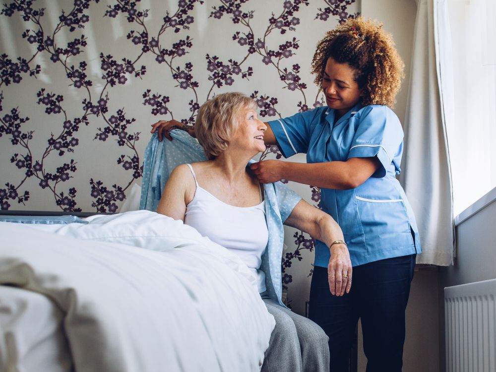 Home carer helping an elderly lady with getting dressed